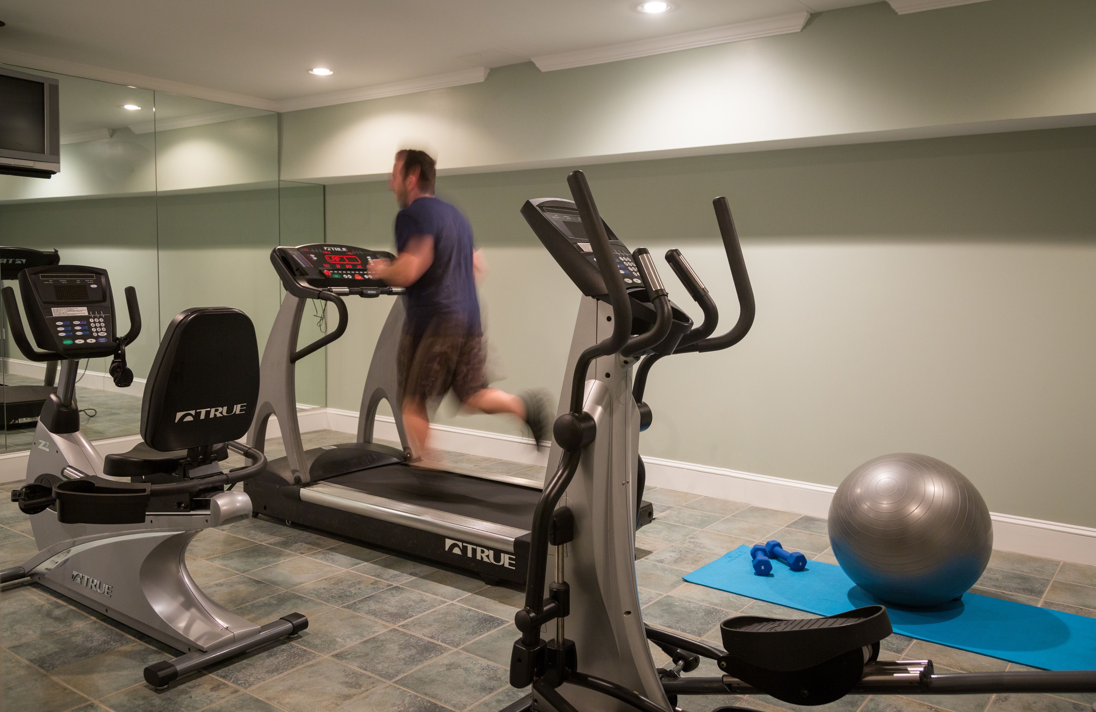 A home gym with a treadmill, exercise bike, and weights.