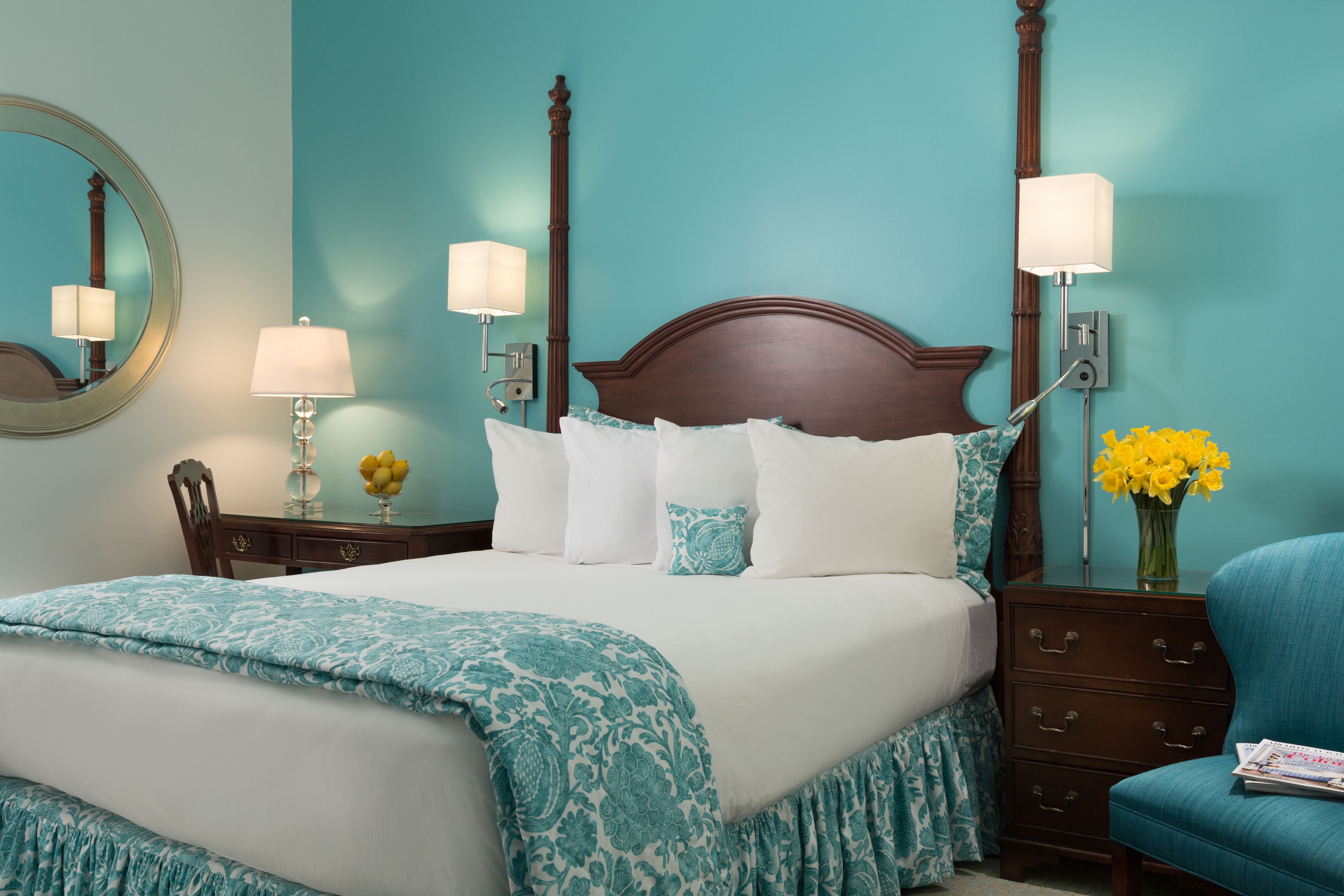 A neatly made bed with a patterned bedspread, a wooden headboard, and two bedside lamps.