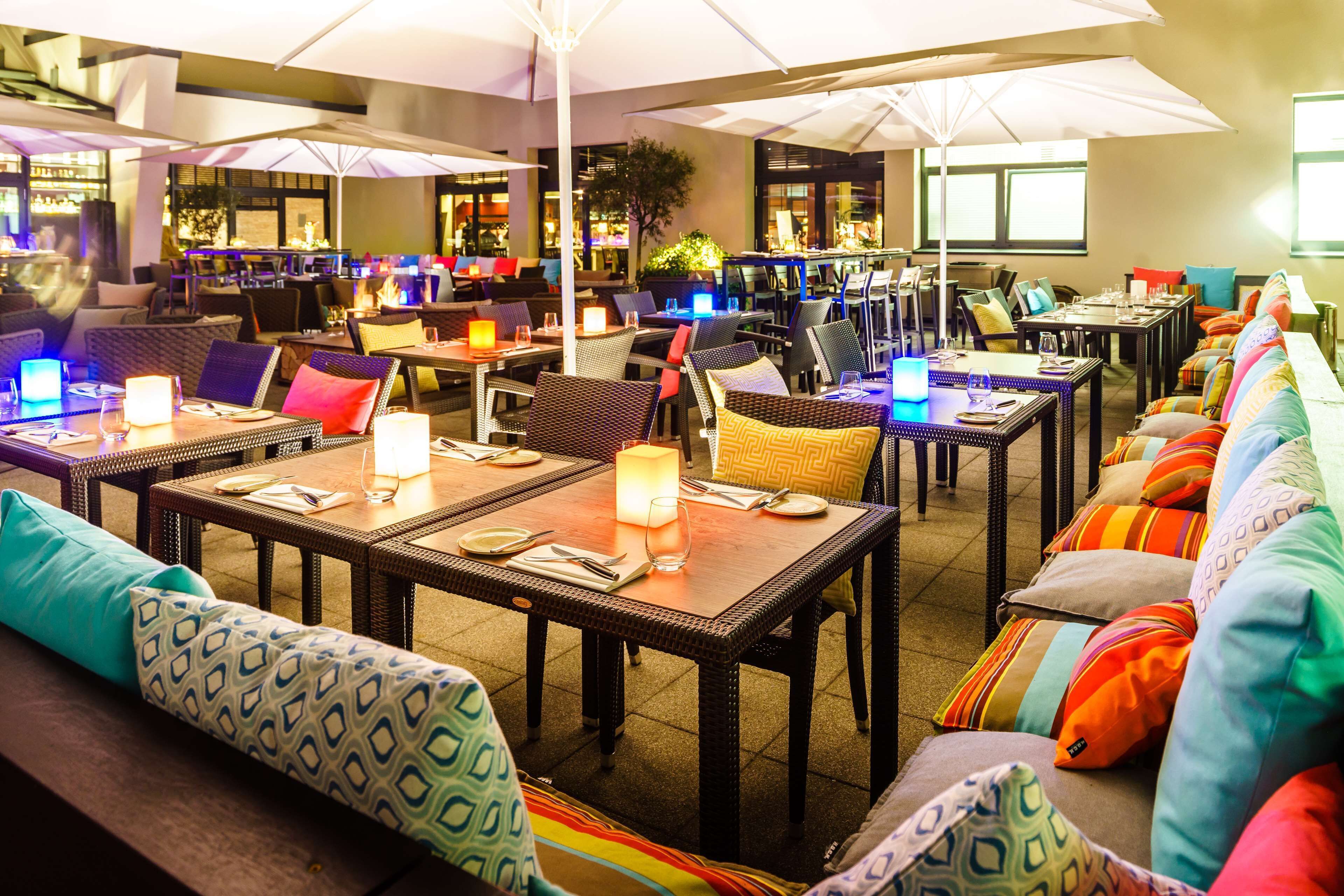 An indoor restaurant with multiple tables and chairs, some with umbrellas.