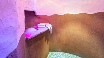 A small, dimly lit room with a tiled floor, a bench, and a towel on a ledge.
