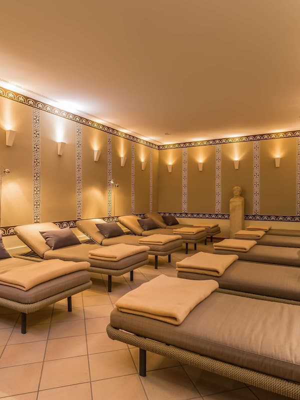 Relax in a serene space with multiple massage therapy beds, each equipped with a pillow and blanket.
