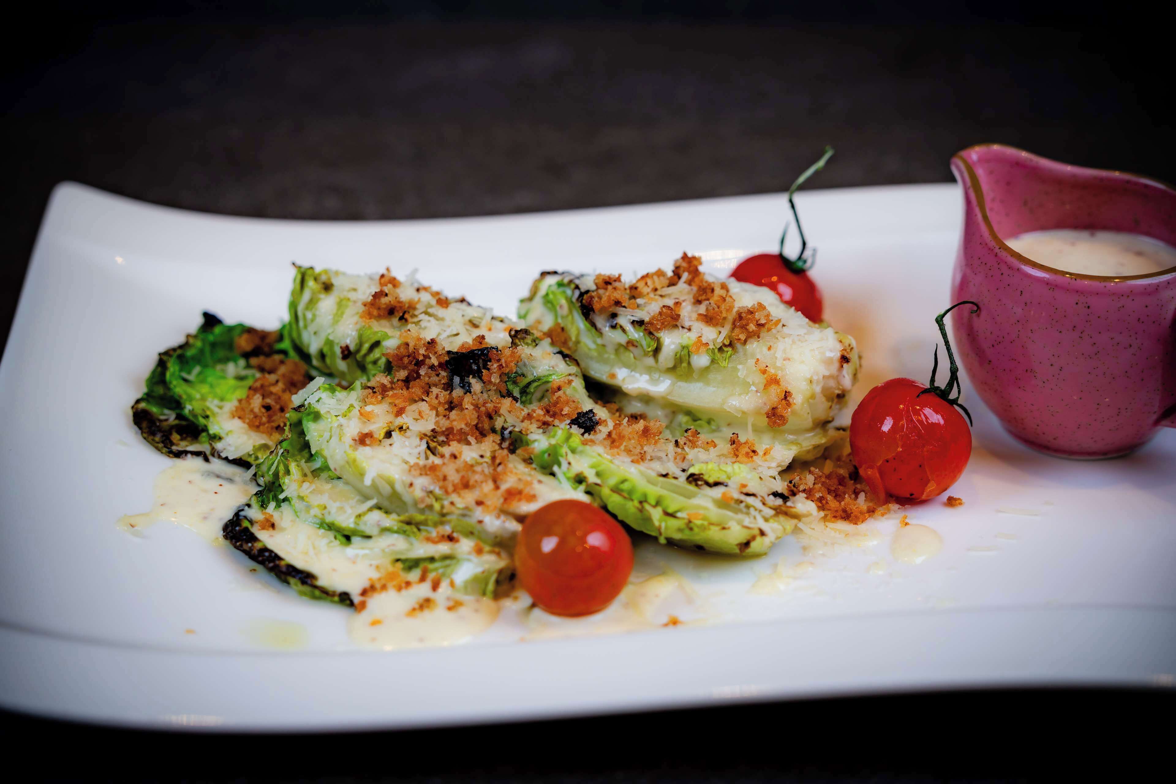 Ein Teller mit Kohlrouladen, dazu Soße und Kirschtomaten.
