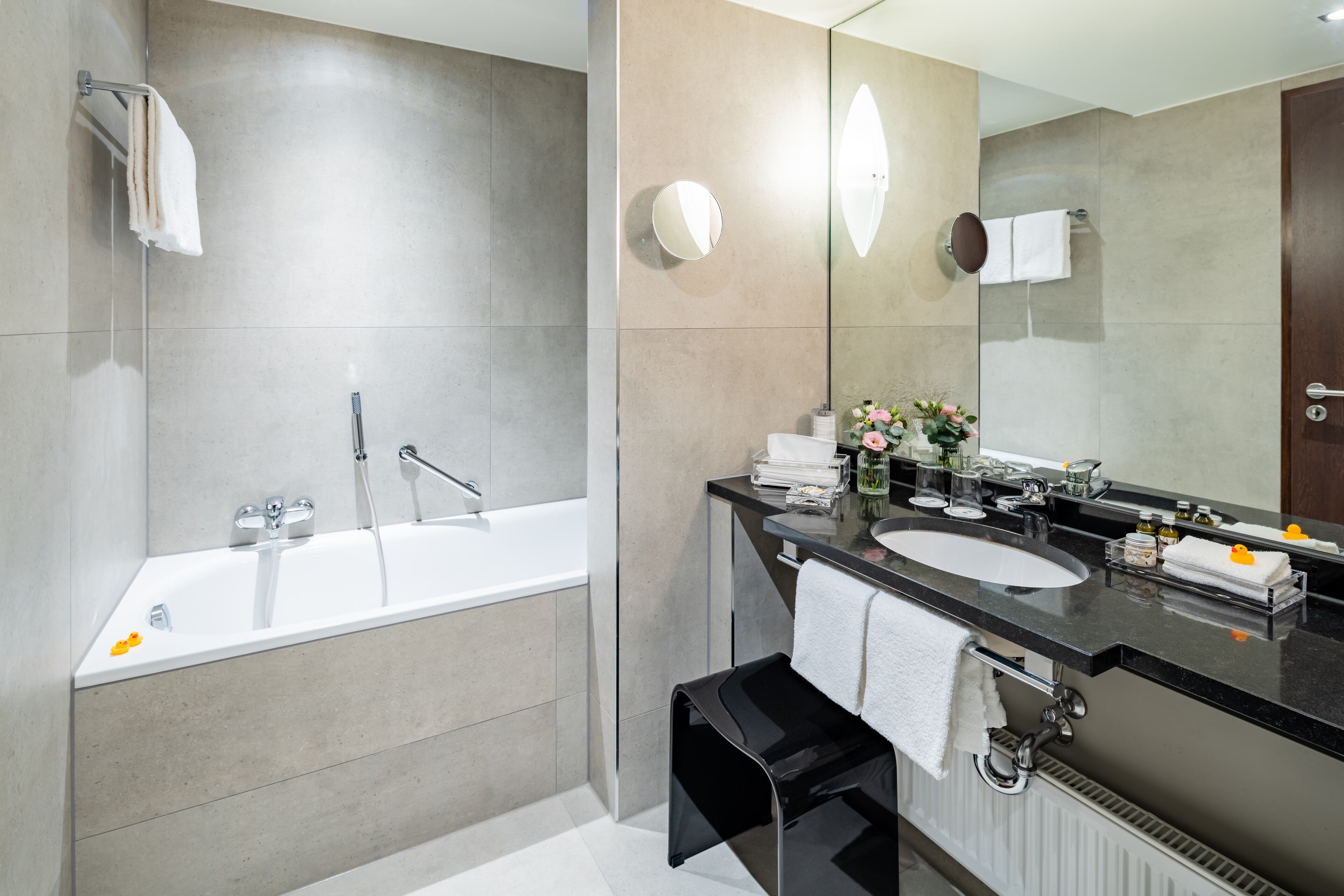 Un bagno moderno con una vasca, uno specchio grande e un mobile lavabo con lavandino e piano di lavoro.