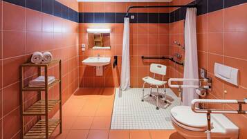 A bathroom with orange and black tiles, a white sink, a toilet, a shower with a white curtain, and a wooden shelf with towels.
