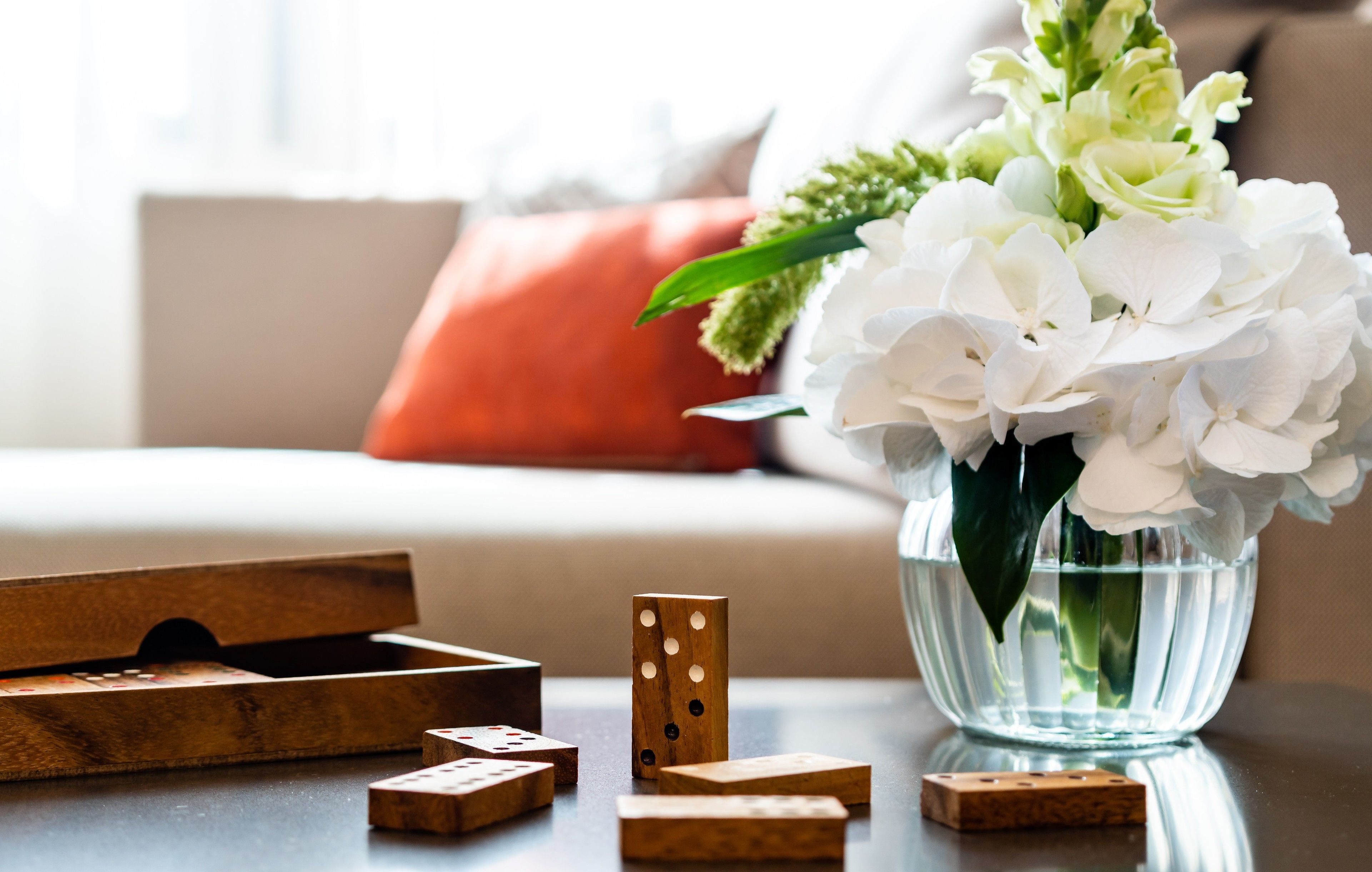A wooden block game set on a table with a vase of white flowers and green leaves.