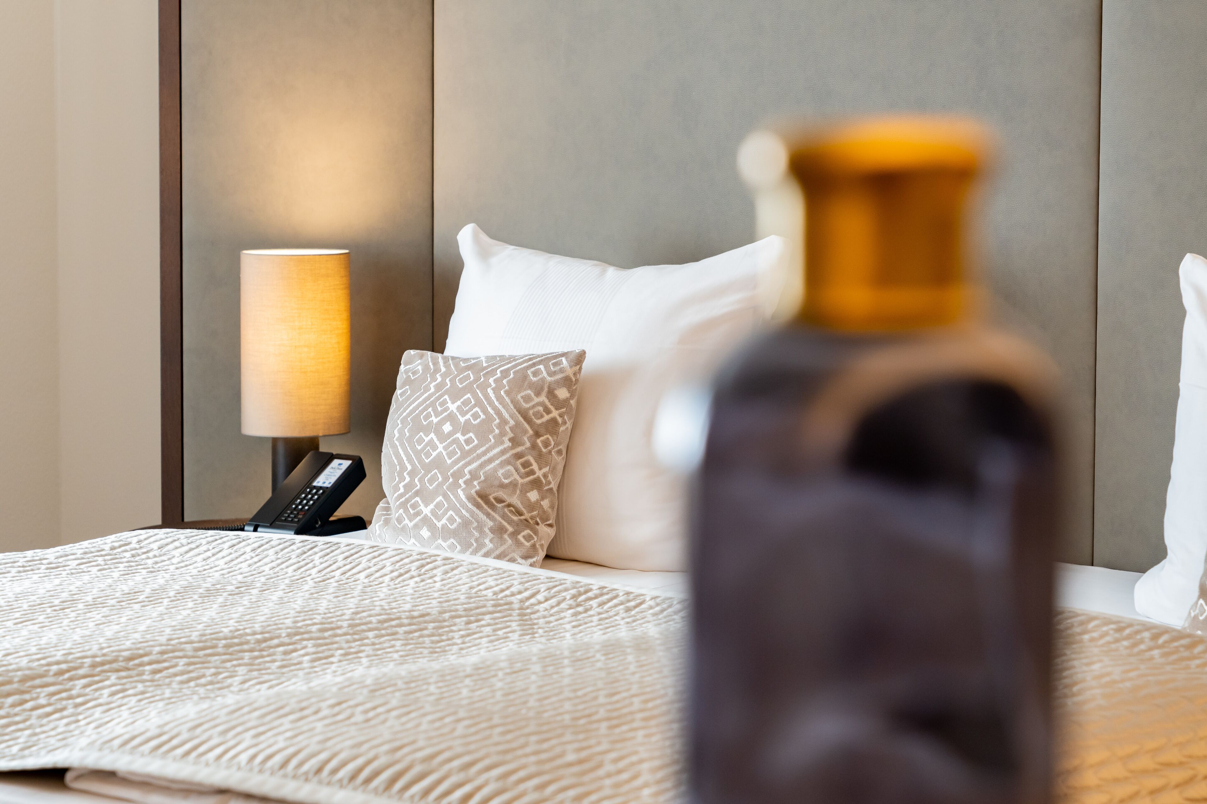 Una habitación de hotel con una cama, una lámpara de noche y un teléfono.