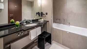 Une salle de bain moderne avec un meuble-lavabo à deux vasques, un grand miroir, un sèche-cheveux, un porte-serviettes et une baignoire.