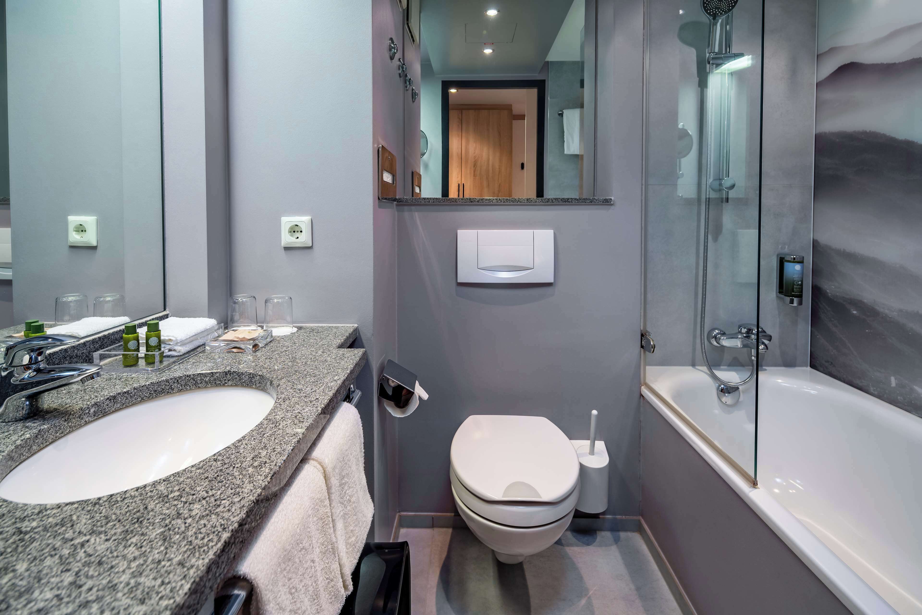 Ein modernes Badezimmer mit einem Waschbecken aus Granit, einer Toilette und einer Duschkabine.