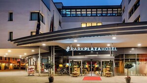 The exterior of the Dark Plaza Hotel with a modern design, featuring a prominent entrance, glass doors, and a red carpet leading to the lobby. - Park Plaza Trier (Trier)