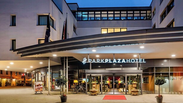 El exterior del Hotel Dark Plaza, con un diseño moderno, presenta una entrada destacada, puertas de cristal y una alfombra roja que conduce al vestíbulo.