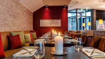 A restaurant with a long table set for dining, candles, and a framed map on the wall.