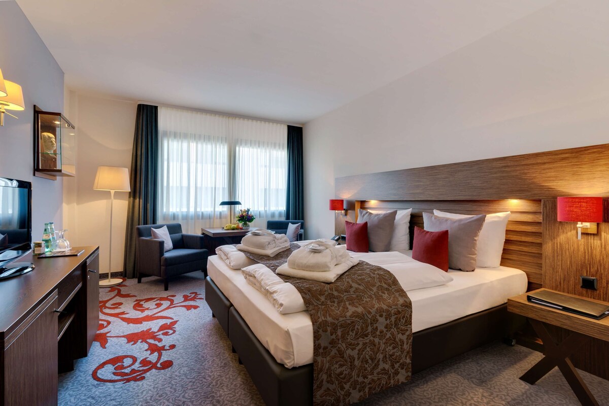 Une chambre d’hôtel avec un grand lit, un bureau, une chaise et un téléviseur.