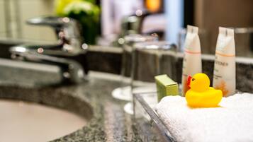 A bathroom with a marble sink, a yellow rubber duck, and toiletries on the counter.