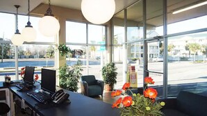 Un espace d’accueil comprenant un comptoir, des chaises et une grande fenêtre donnant sur la rue.