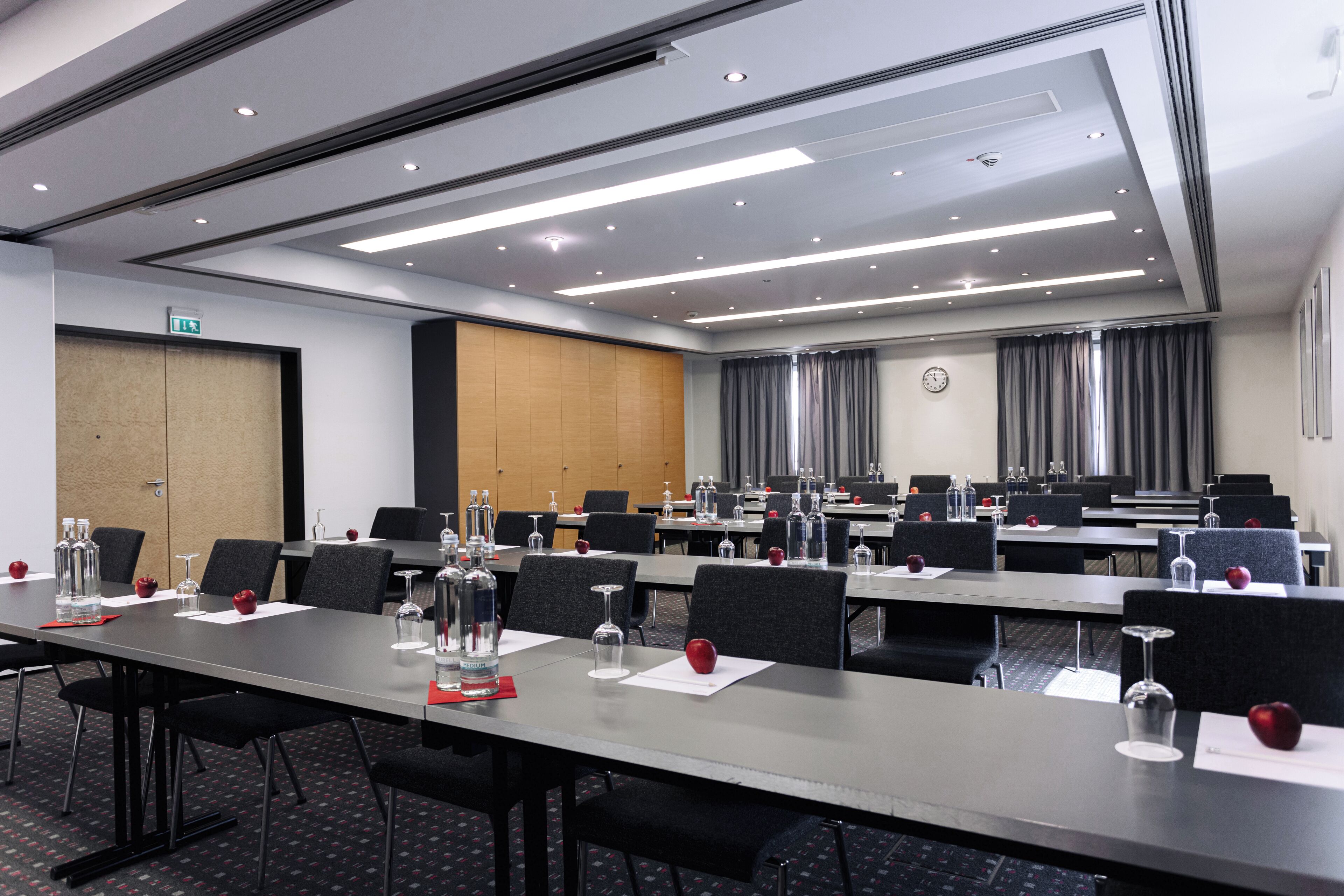 Une salle de conférence équipée de longues tables, de chaises et de verres.