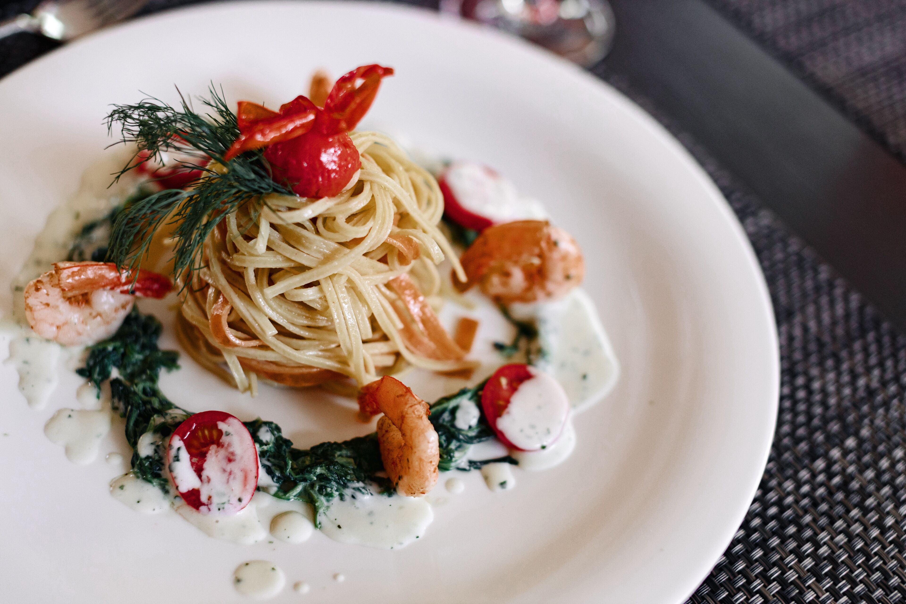 A plate of pasta with shrimp, radishes, and a garnish of dill.