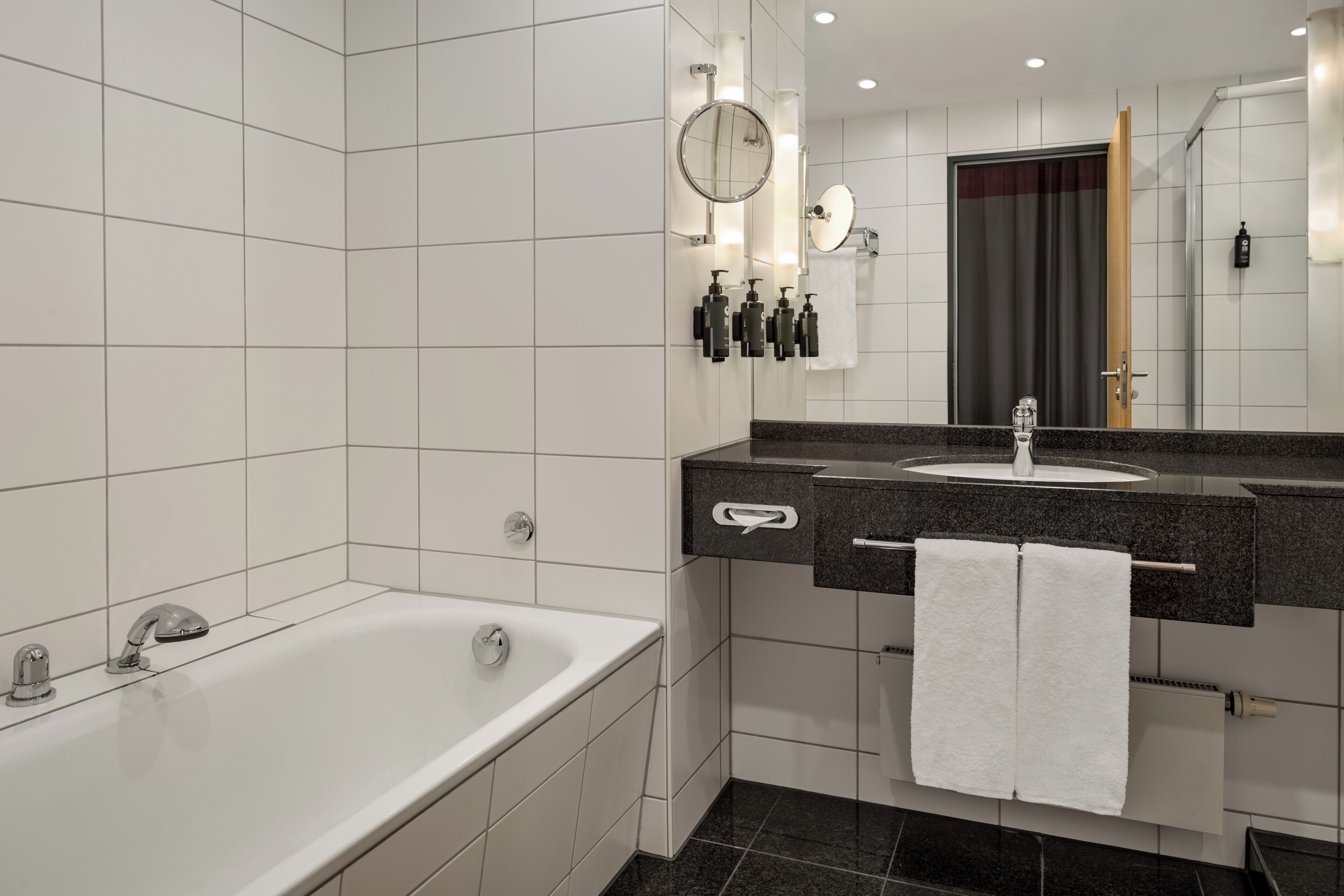A modern bathroom with a bathtub, a sink with a mirror, and a towel rack.