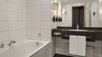 A modern bathroom with a bathtub, a sink with a mirror, and a towel rack.