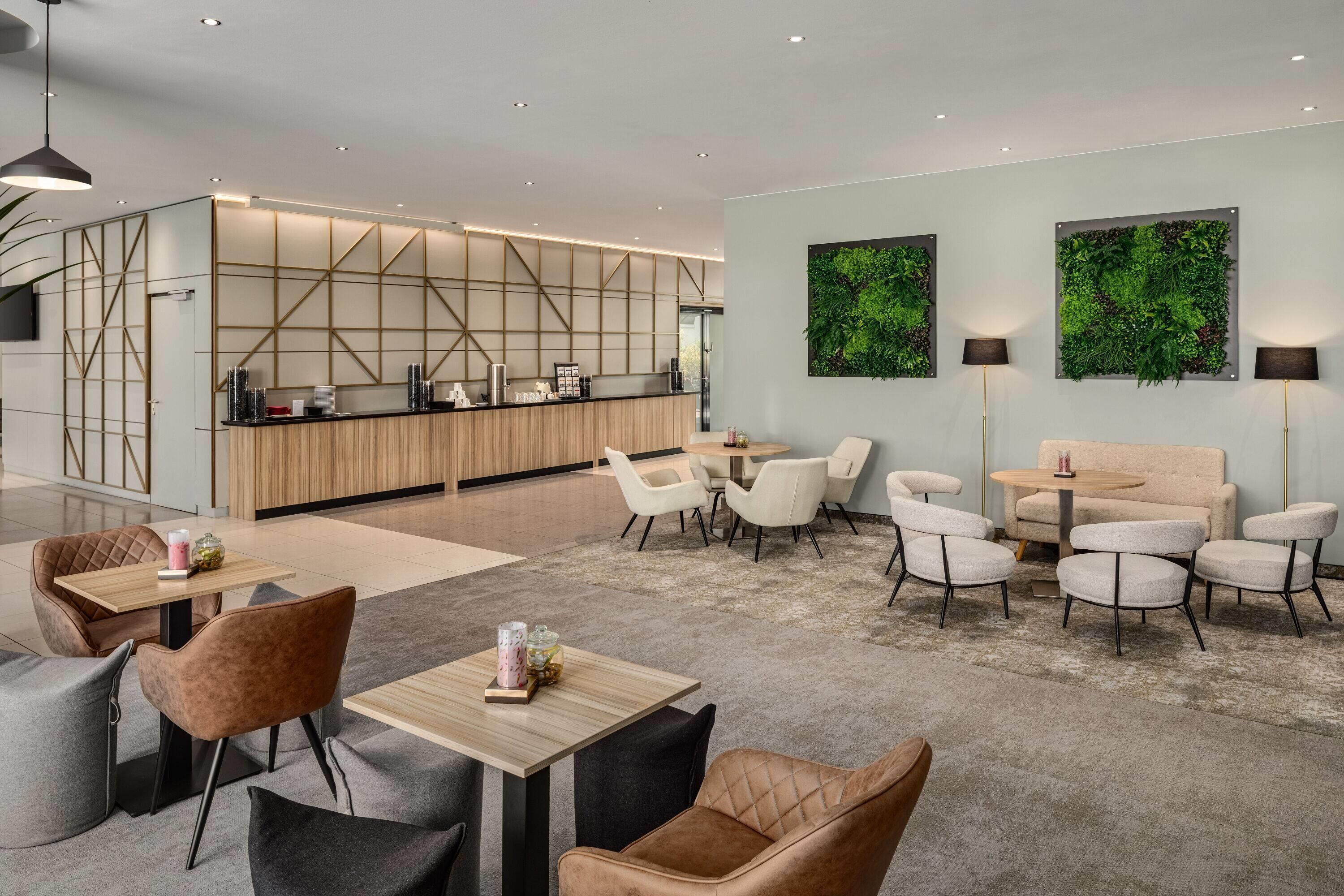 Een moderne hotel lobby met een receptiebalie, een zithoek en een keuken op de achtergrond.