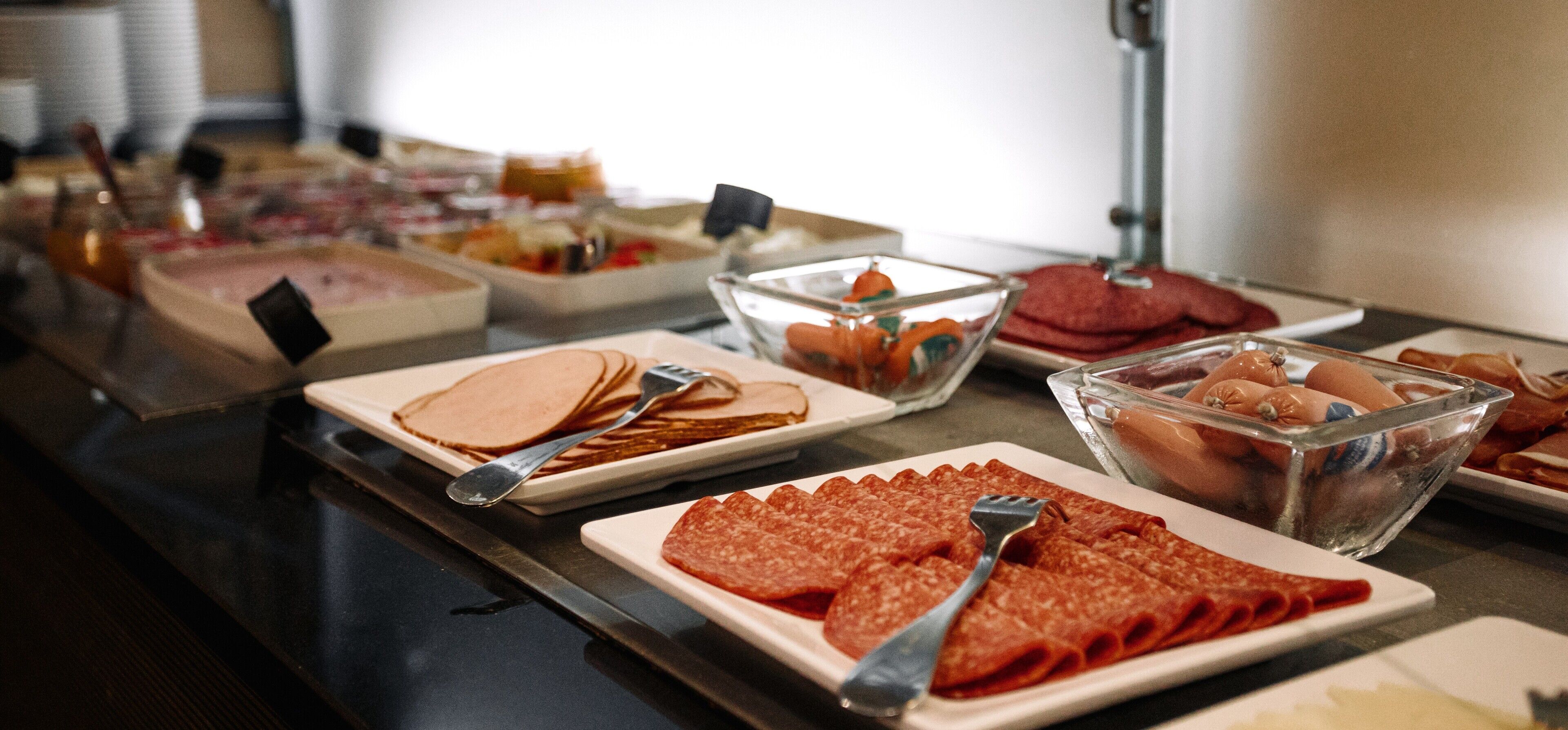 Ein reichhaltiges Buffet mit verschiedenen Speisen, darunter Aufschnitt, Eiern und Gebäck.
