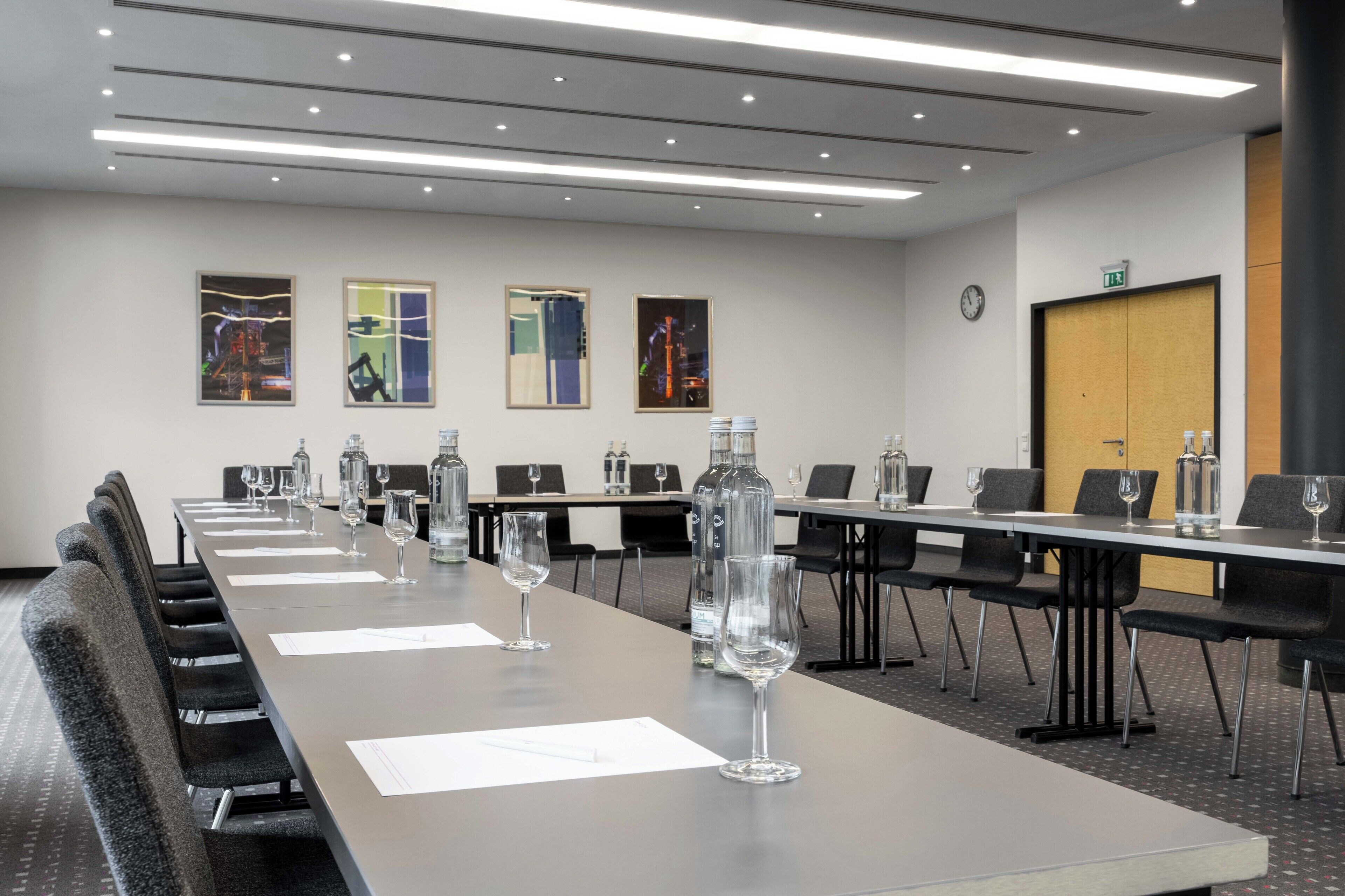 A conference room with a long table, chairs, water bottles, and wine glasses.