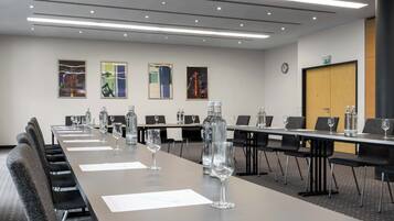 A conference room with a long table, chairs, water bottles, and wine glasses.
