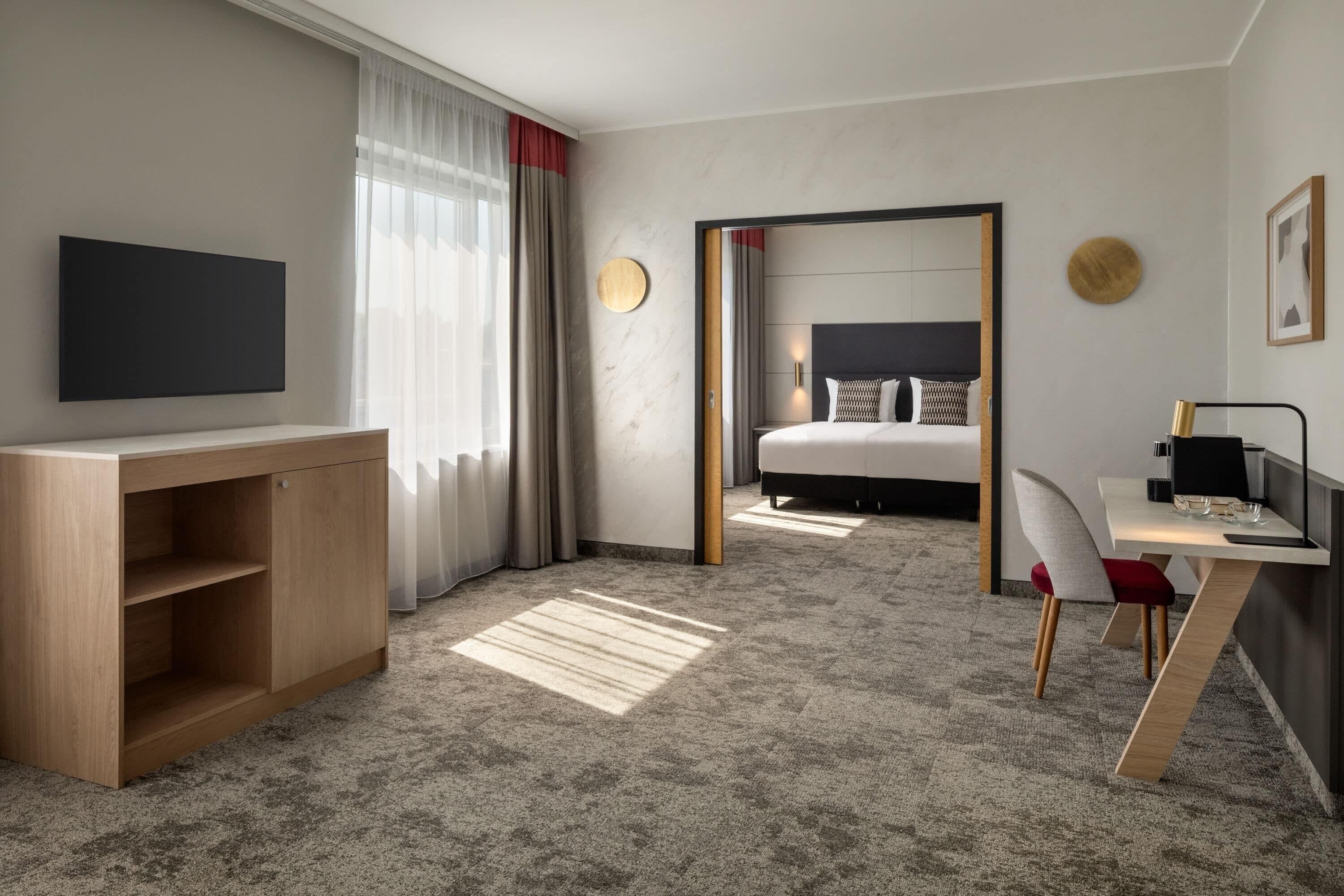 A hotel room with a bed, a desk, a TV, and a mirror.
