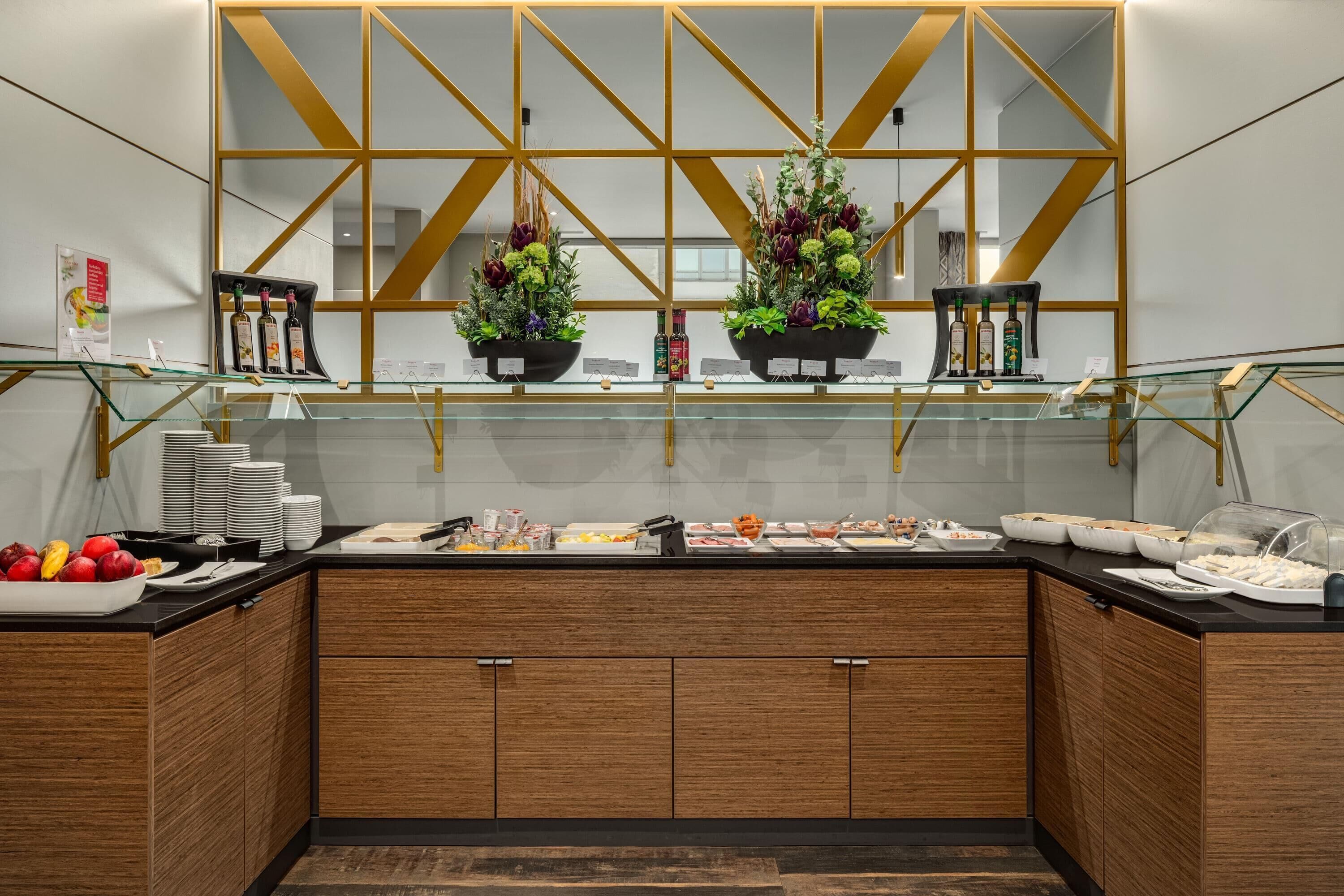 A modern buffet setup with glass display cases, wooden cabinets, and decorative plants.