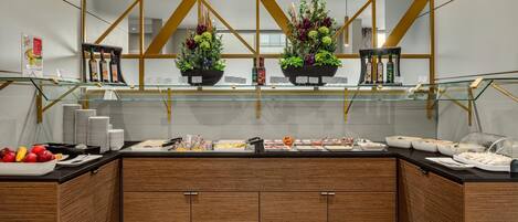 A modern buffet setup with glass display cases, wooden cabinets, and decorative plants.