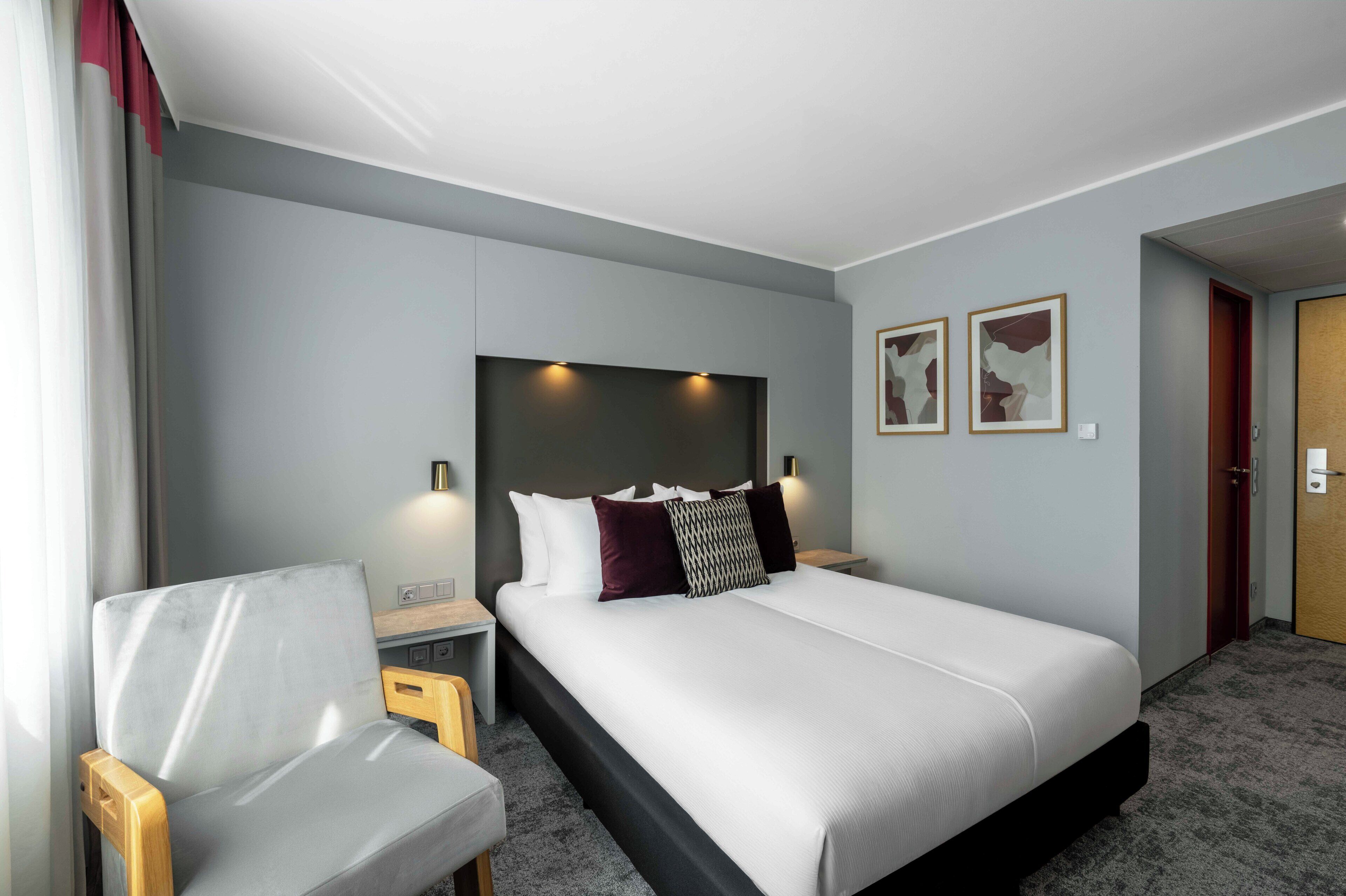 Una habitación de hotel con cama, una silla, un escritorio y un armario.