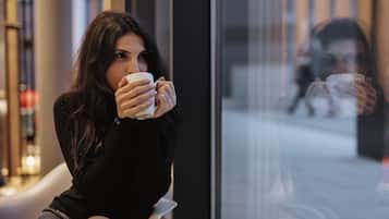 A person sitting on a bench inside a building, holding a cup.