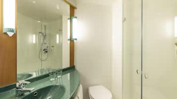 Een moderne badkamer met een douche met glazen wand, een wastafel met spiegel en een toilet.