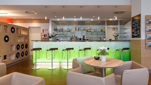 Un bar moderno con mostrador, taburetes y una zona de estar con una mesa redonda.