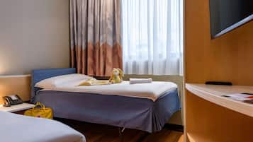Relax in comfort with a neatly made bed, plush toy, and a book at your fingertips.