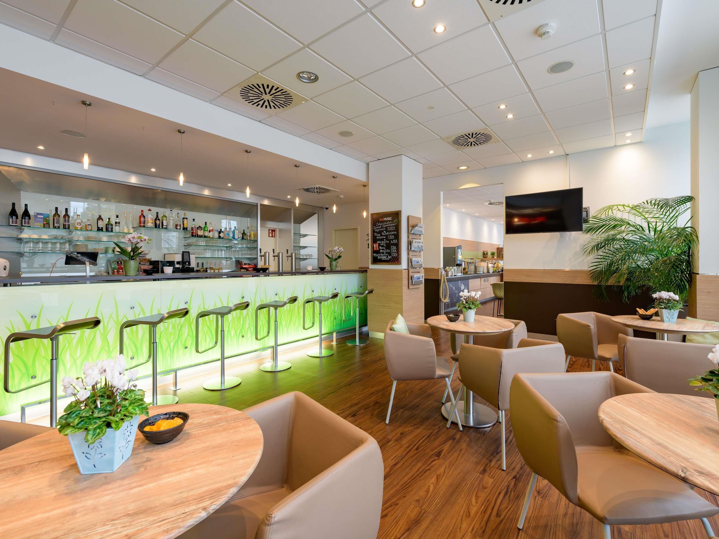 A modern bar area with a counter, bar stools, and a seating area with round tables and chairs.