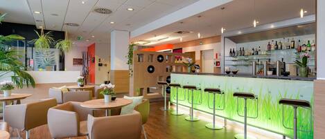 Uma área de bar moderna com balcão de neon verde, diversos arranjos de assento e piso de madeira.