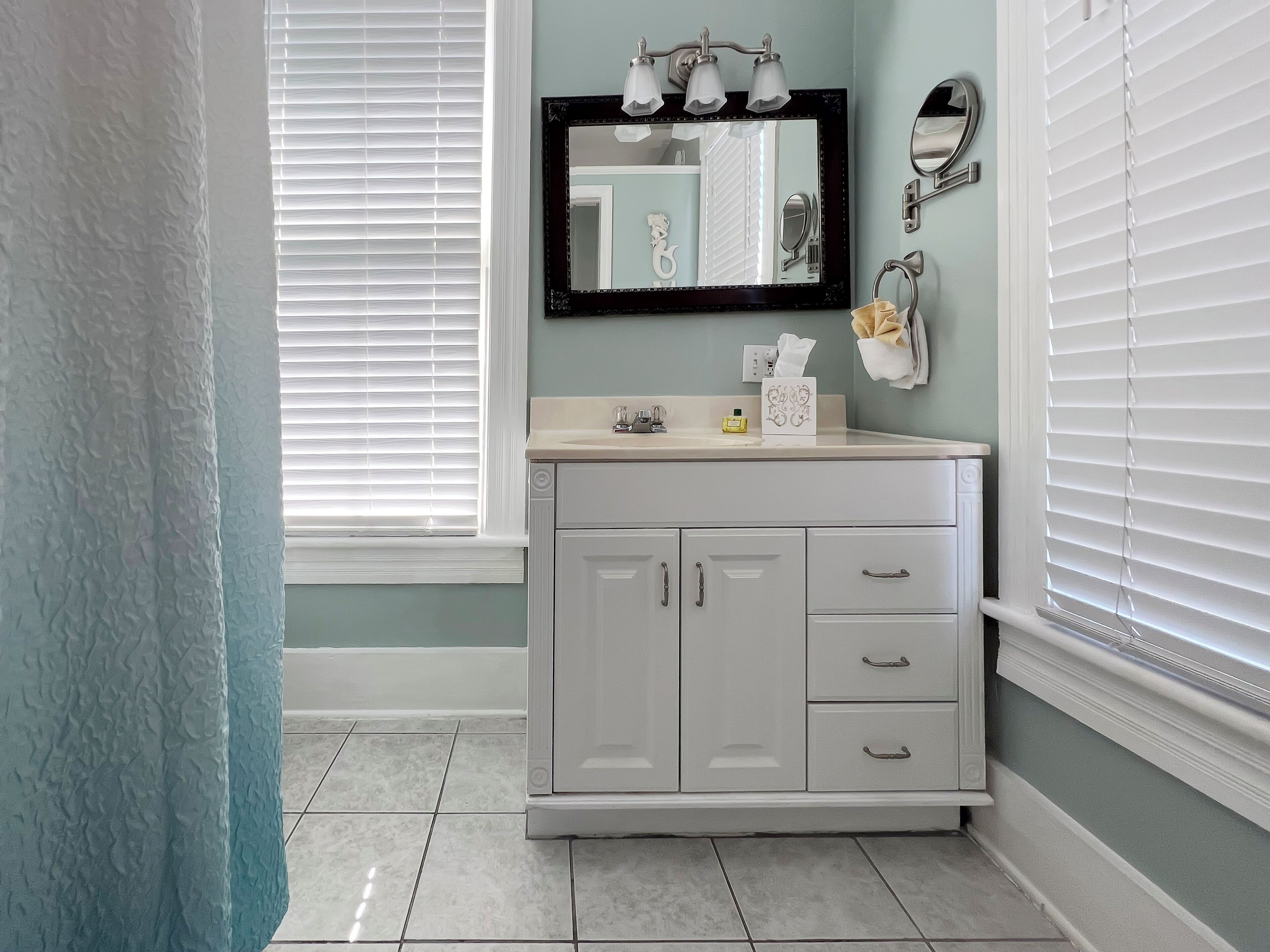 Une salle de bain avec un meuble-lavabo blanc, un miroir avec éclairage intégré et un porte-serviettes.
