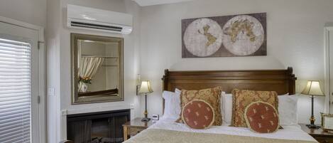 A hotel room with a large bed, a fireplace, a world map artwork, and a ceiling fan.