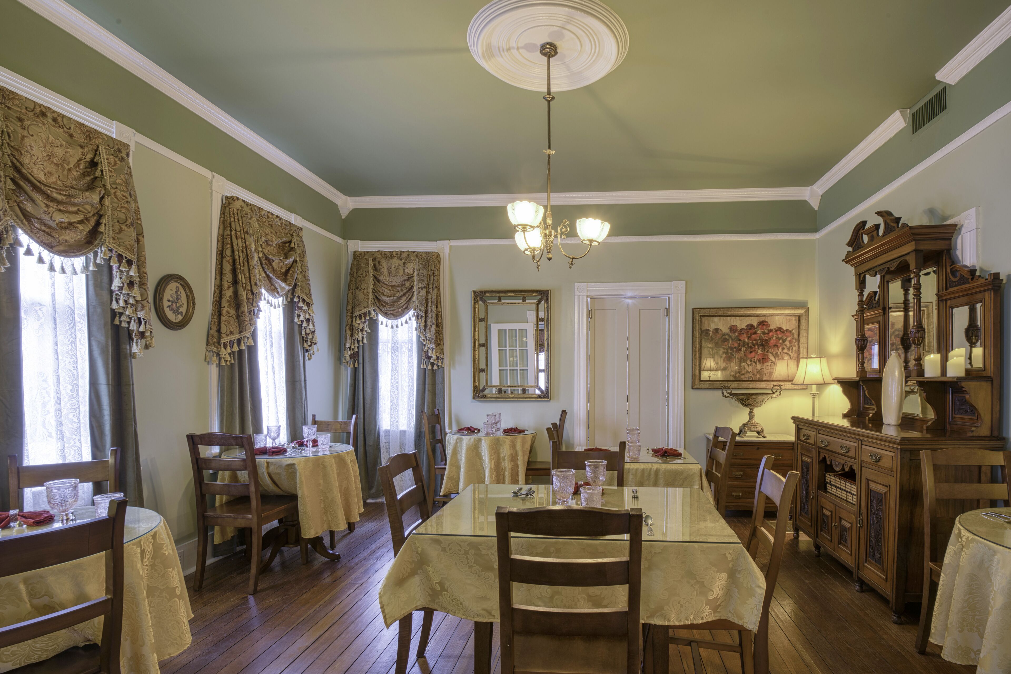 Comedor con candelabro, muebles de madera y un espejo grande.