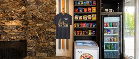 Un mur de pierres, un t-shirt suspendu, des étagères remplies d’en-cas et un distributeur automatique de boissons.