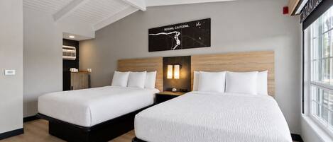 A hotel room with two beds, a wooden headboard, a wall-mounted map, and a window.