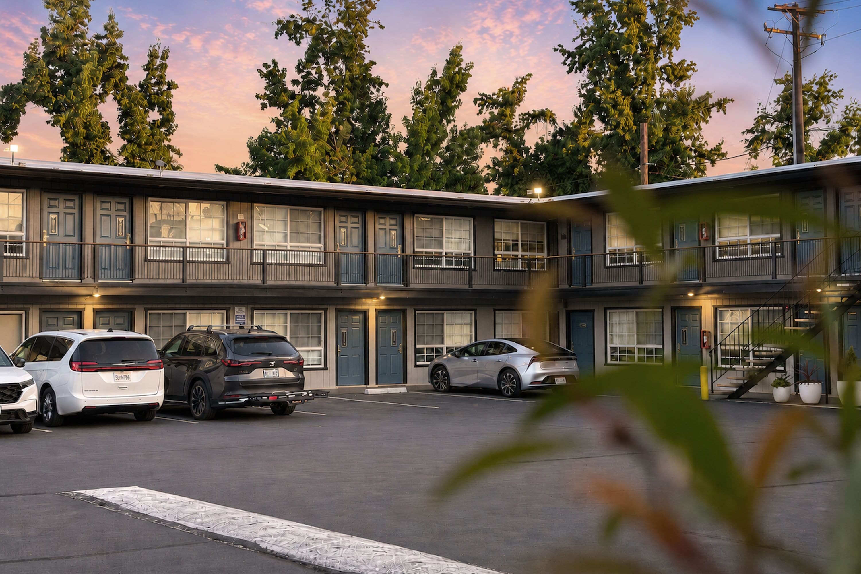A motel with multiple rooms, a parking lot, and a staircase leading to the entrance.