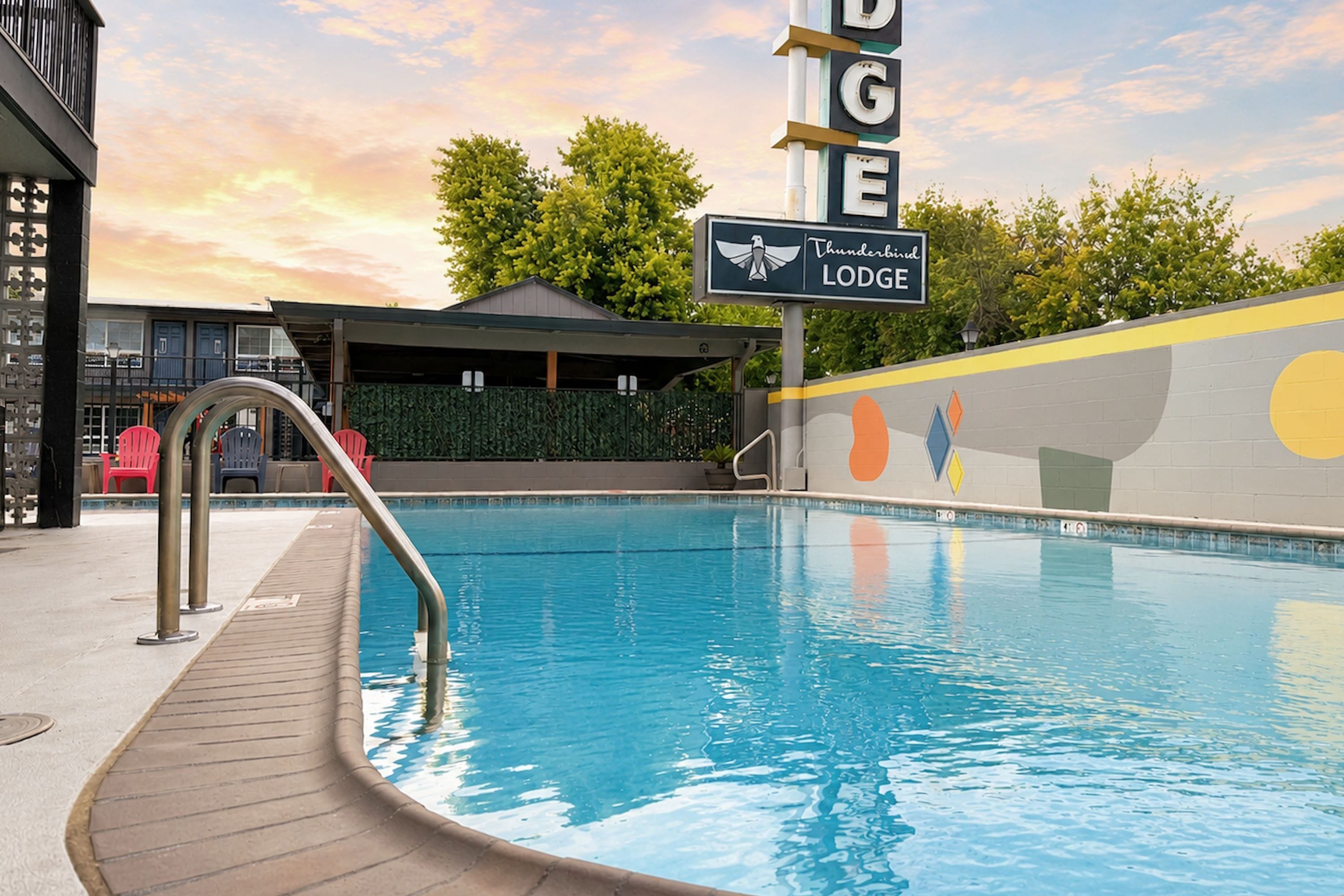 A swimming pool with a wooden deck, a lounge area, and a sign for 'Thunderbird Lodge.'