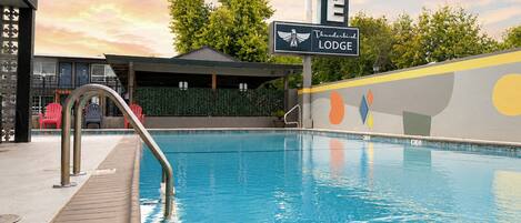 A swimming pool with a wooden deck, a lounge area, and a sign for 'Thunderbird Lodge.'
