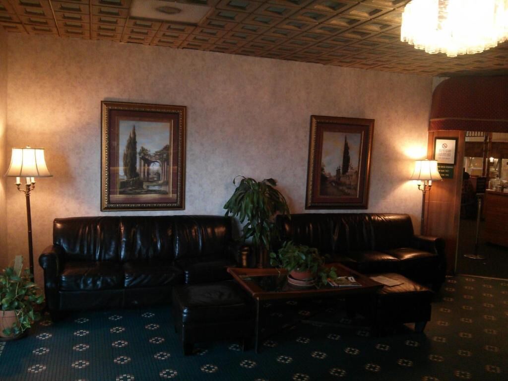 A hotel lobby with leather sofas, a coffee table, two framed paintings, and a chandelier.
