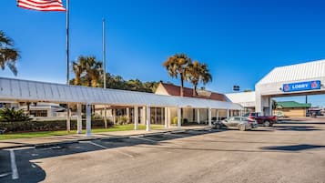A hotel with a covered outdoor area, a flagpole with an American flag, and a sign indicating a lobby.