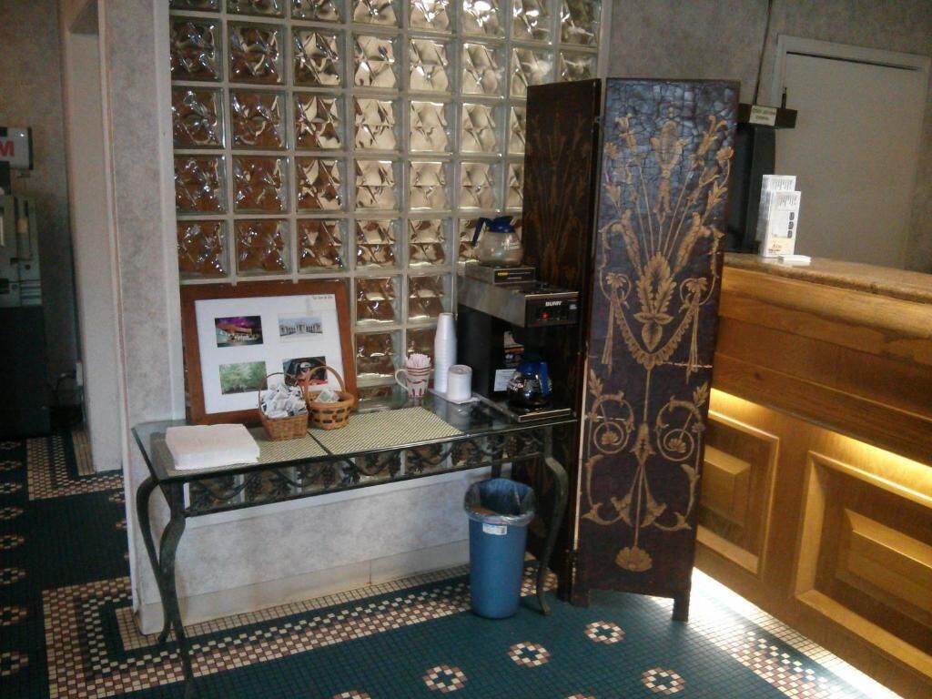 Une chambre d’hôtel avec un comptoir de réception, une poubelle, une photo encadrée et un sol à motifs.