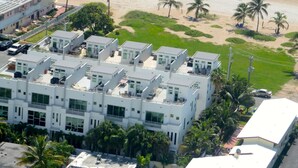 An aerial view of a coastal hotel with multiple buildings, a beach, and a parking area.