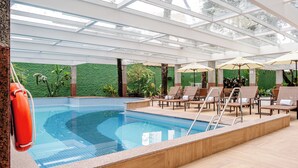 An indoor swimming pool with a glass ceiling, lounge chairs, and a lifebuoy. - Blue Tree Premium Verbo Divino (São Paulo)