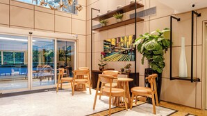 A lobby with a reception desk, wooden chairs, a large potted plant, and a view of the outside through glass doors. - Blue Tree Premium Verbo Divino (São Paulo)